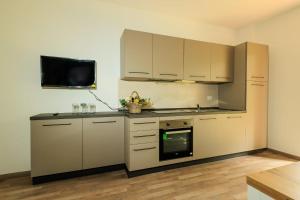 a kitchen with white cabinets and a tv on the wall at Residence San Francesco in Tirrenia