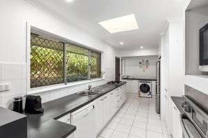 a white kitchen with a sink and a window at Stylish Home in Fig Tree Pocket near Lone Pine in Brisbane