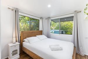 a bedroom with a white bed and two windows at Stylish Home in Fig Tree Pocket near Lone Pine in Brisbane