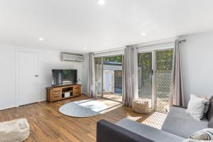 a living room with a couch and a tv at Stylish Home in Fig Tree Pocket near Lone Pine in Brisbane