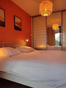 a bedroom with a large white bed with an orange wall at Séjour de rêve à La Grande Motte T2 entièrement neuf, clim, wifi, parking privé in La Grande-Motte