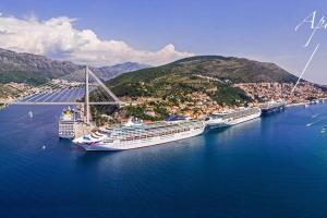 drei Kreuzfahrtschiffe, die in der Nähe einer Brücke im Wasser angedockt sind in der Unterkunft Apartment MIAMAR with port sea view in Dubrovnik