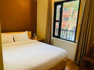 een slaapkamer met een wit bed en een raam bij Hotel Aagaman - Best Family Hotel in Bandipur in Bandipur