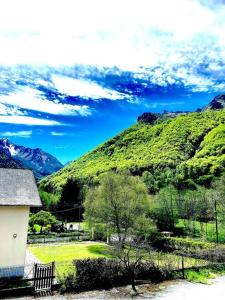 a green hill with a house and a mountain at Appartement Chez Place à Estaing in Estaing
