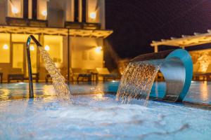- une fontaine dans la piscine la nuit dans l'établissement ILIADA-ODYSSEAS RESORT, à Perivolos