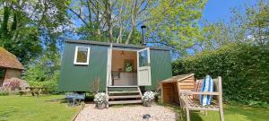 a green tiny house in a yard with a chair at Halfway Bridge in Midhurst