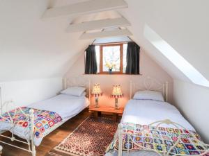 a attic bedroom with two beds and a window at Brodie East Cottage in Forres