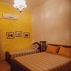 2 łóżka w pokoju z żółtymi ścianami w obiekcie nostra casa suite w mieście Palermo