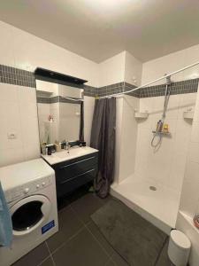 een badkamer met een wasmachine, een wastafel en een wasmachine bij Studio Design & Cosy avec Parking in Issy-les-Moulineaux