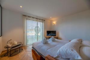 - une chambre avec un grand lit et une grande fenêtre dans l'établissement Appartements Côté Sud, à LʼÎle-Rousse
