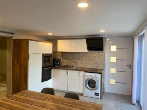 cocina con armarios blancos, lavadora y secadora en Appartement 2 pièces cozy au calme en Mitry-Mory
