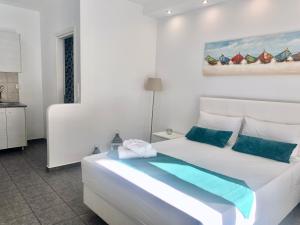 a white bedroom with a large white bed with blue pillows at Anemos Studios in Adamantas