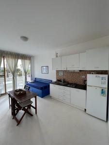 eine weiße Küche mit einem Tisch und einem Kühlschrank in der Unterkunft Útulný apartmán na Praia de Chaves, Boa Vista in Sal Rei