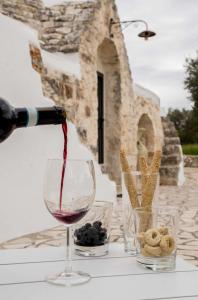 Trullo Ostuni Terre di Santa في أوستوني: يتم صب زجاجة من النبيذ في كأس النبيذ