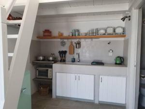 una cocina con armarios blancos y fregadero en Merope seaside house, en Platis Yialos Sifnos