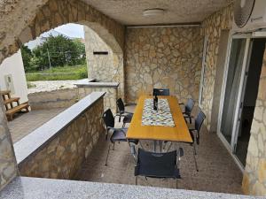una mesa y sillas en una habitación con una pared de piedra en Apartments ANTONIA - S. Novalja, en Stara Novalja