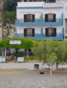 un bâtiment bleu et blanc avec des bancs devant lui dans l'établissement Venetia, à Tsoútsouros