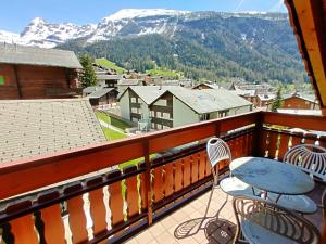 a balcony with a table and chairs and mountains at Château 43o in Leukerbad