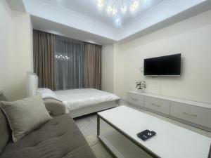 - un salon avec un canapé, un lit et une télévision dans l'établissement Апартамент КРИСТАЛЛ, à Bishkek