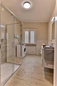 y baño con ducha, lavabo y lavadora. en Appartamento Stella -Rebomaholidays, en Olzano