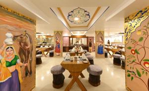 un restaurante con mesas, sillas y pinturas en las paredes en Hotel Ganga Ratan, en Agra