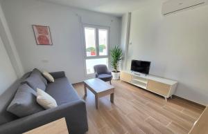 a living room with a gray couch and a tv at Apartamento a estrenar en Planta Primera C con piscina in Barbate