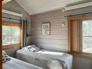 Duas camas num quarto com paredes e janelas de madeira em Casa Vierumäki em Vierumäki