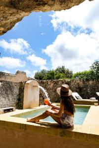 una mujer con sombrero sentada junto a una piscina en Masseria D'Erchia en Monopoli