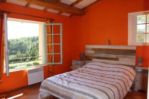 um quarto com paredes cor-de-laranja, uma cama e 2 janelas em Mas Chamarel, la Provence entre vignes et oliviers proche de la mer em Sanary-sur-Mer