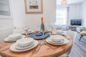 una mesa de comedor con platos y copas de vino en Canol Y Bryn - 3 Bedroom Holiday Home - Tenby en Tenby