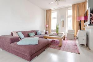 een woonkamer met een paarse bank en een tafel bij Zandvoort Zenith - Beautiful Apartment in Zandvoort