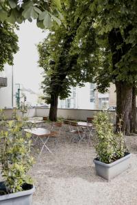 un patio avec des tables, des chaises et des arbres dans l'établissement Hotel Cristallo, à Landshut