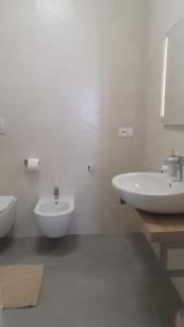 uma casa de banho branca com 2 lavatórios e um WC em Casa di Monique 1 em Bari Palese