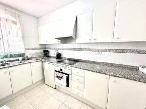 a white kitchen with white cabinets and a sink at Three bedroom apartment, PRIME Javea location in Jávea