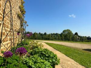 a garden with purple flowers next to a stone wall at Cotswold Retreat in Great Tew