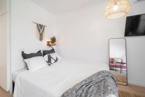 a white bedroom with a large bed and a mirror at Benalmadena Jupiter Sunsea View Apartments in Benalmádena