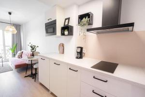 eine Küche mit weißen Schränken und einem Tisch im Zimmer in der Unterkunft Benalmadena Jupiter Sunsea View Apartments in Benalmádena