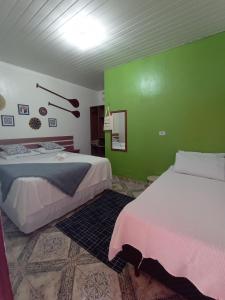 a room with two beds and a green wall at Pousada e Hostel Coração Verde, Vários Tipos de Acomodações 300 metros da Orla in Alter do Chao