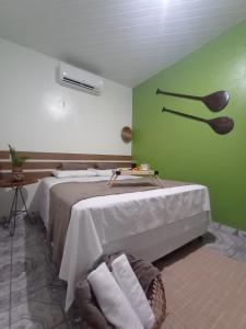 1 dormitorio con cama y pared verde en Pousada e Hostel Coração Verde, Vários Tipos de Acomodações 300 metros da Orla, en Alter do Chao