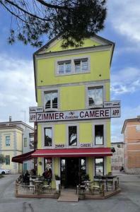 a yellow building with tables and chairs in front of it at Zimmer Umago in Umag