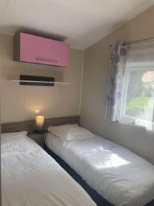 two beds in a small room with a window at Mobile home in Meschers-sur-Gironde