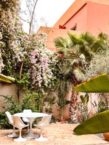 una mesa y sillas en un jardín con flores en L'Annexe-Villa patio arboré & piscine privée, en Marrakech