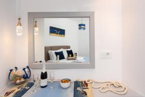 アルハンゲロスにあるAntonia's Apartmentsのテーブルの上に鏡(ワイングラス付)とベッド