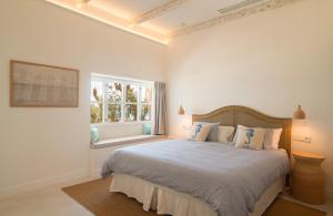 a white bedroom with a large bed and a window at The Sea Club in Cala Ratjada