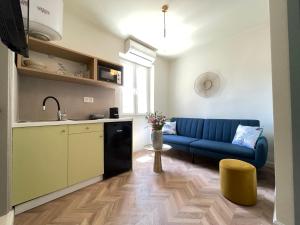 een woonkamer met een blauwe bank en een keuken bij Piazza San Rocco Apartments in Corfu-stad