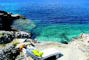 a view of the ocean from a beach with a chair at PaxosBlue Suites & Villas in Gaios