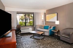 a hotel room with a couch and a tv at Courtyard by Marriott Oakland Airport in Oakland