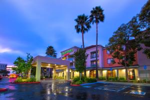 a hotel with palm trees in a parking lot at Courtyard by Marriott Oakland Airport in Oakland
