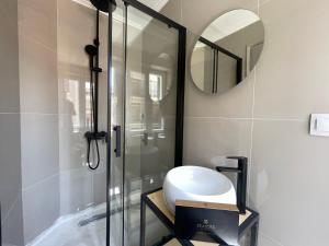 een badkamer met een douche, een wastafel en een spiegel bij Piazza San Rocco Apartments in Corfu-stad