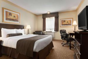a hotel room with a bed and a flat screen tv at Days Inn & Suites by Wyndham Sault Ste. Marie ON in Sault Ste. Marie
